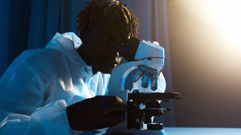 Investigador mirando por un microscopio en un laboratorio, imagen del estudio sobre la duración del viaje psicodélico