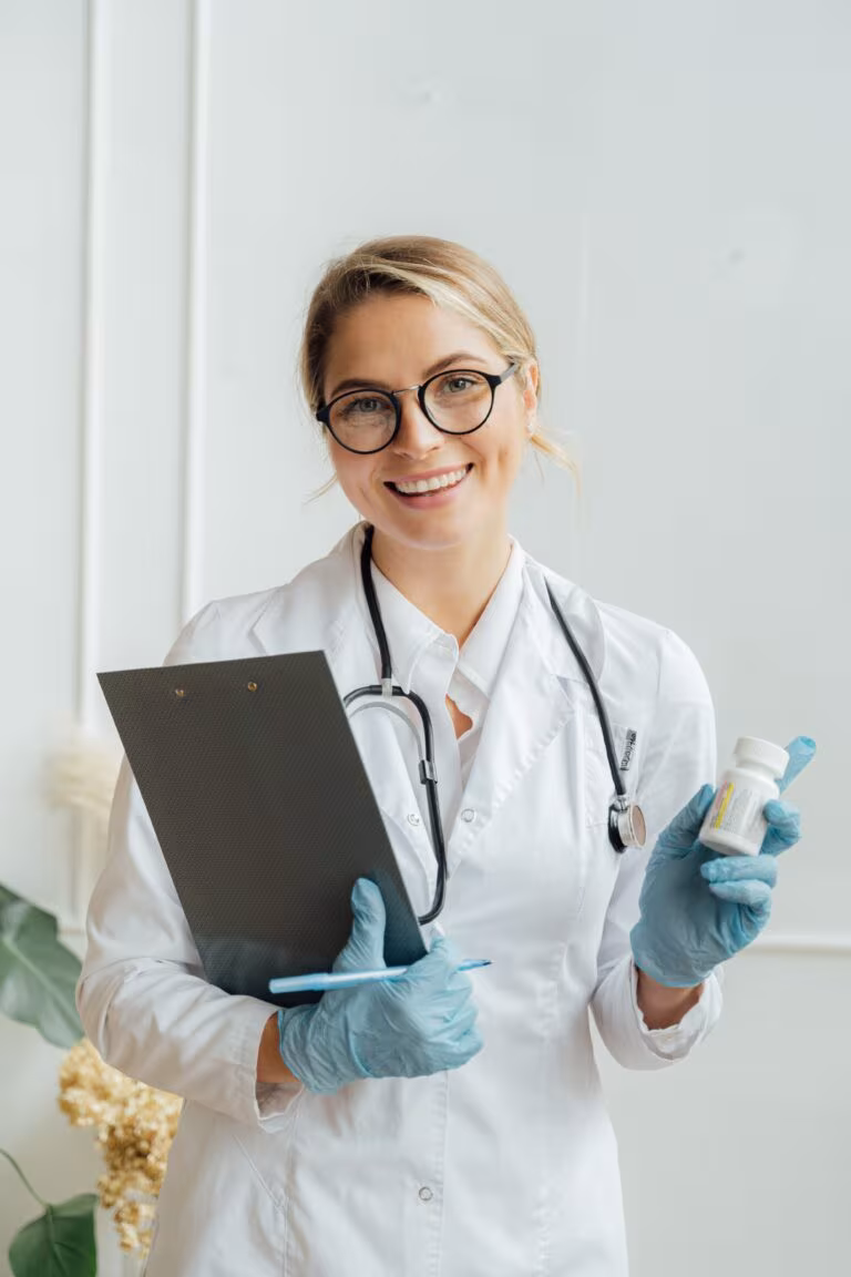 Doctora sonriente con bata, estetoscopio y carpeta, imagen de la autorización de la terapia asistida con psicodélicos en Australia