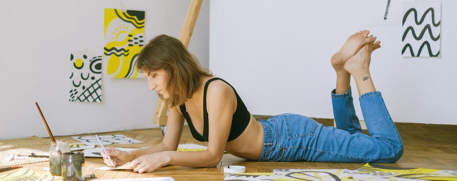 Joven tumbada en el suelo pintando con acuarelas, sobre un gran estudio de psilocibina contra la depresión