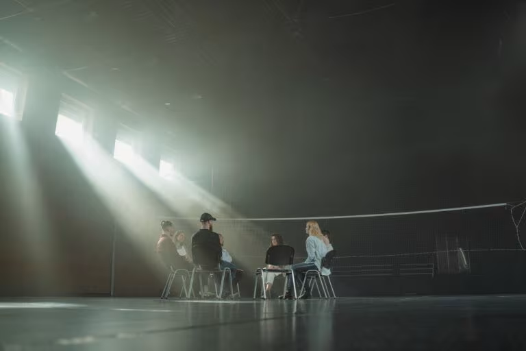 Personas sentadas en círculo bajo haces de luz, imagen de qué es la integración psicodélica