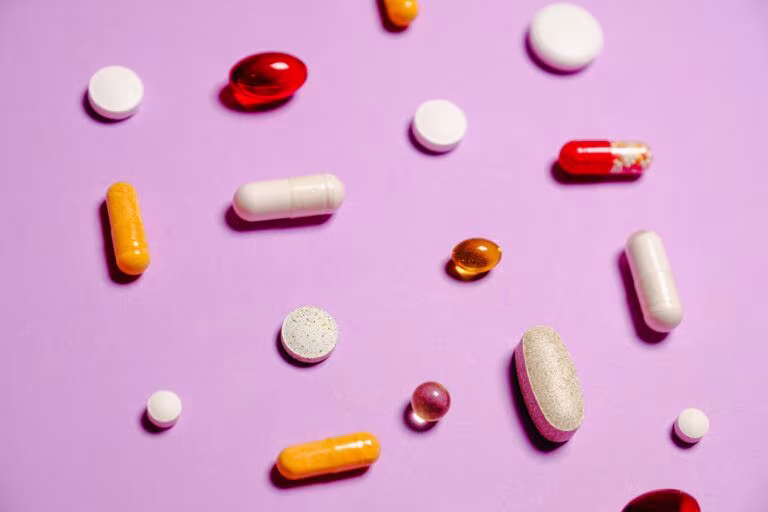 Pastillas y cápsulas de colores sobre fondo rosa, imagen de las interacciones farmacológicas de los psicodélicos