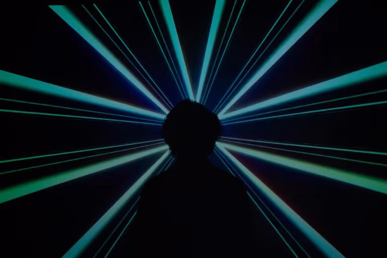 Silueta de una persona ante rayos de luz azul, imagen de cómo el DMT cambia la percepción visual y las alucinaciones