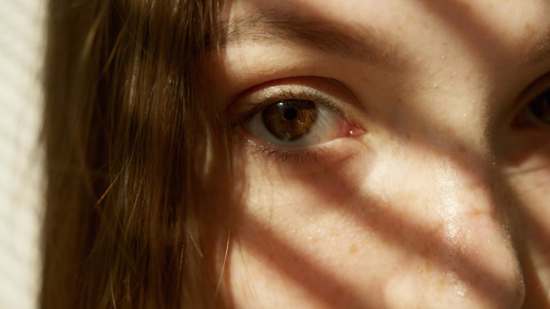 Ojo de una mujer entre sombras de persiana, imagen de los psicodélicos sin efectos alucinógenos y el debate sobre su terapia