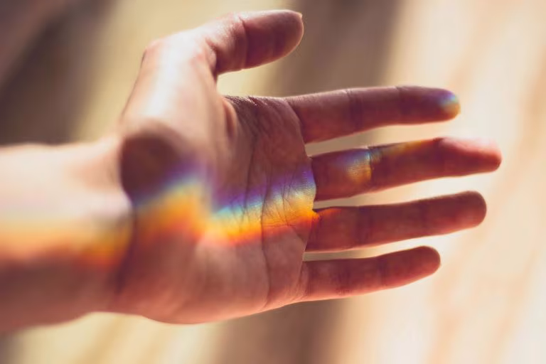 Mano abierta con un reflejo de luz de colores, imagen del papel de los psicodélicos en la sexualidad