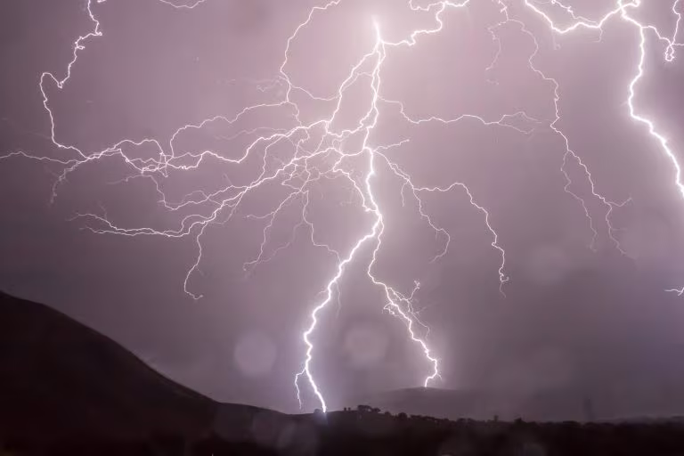 Relámpagos sobre una montaña en un cielo nocturno, imagen de cómo medir el resplandor psicodélico