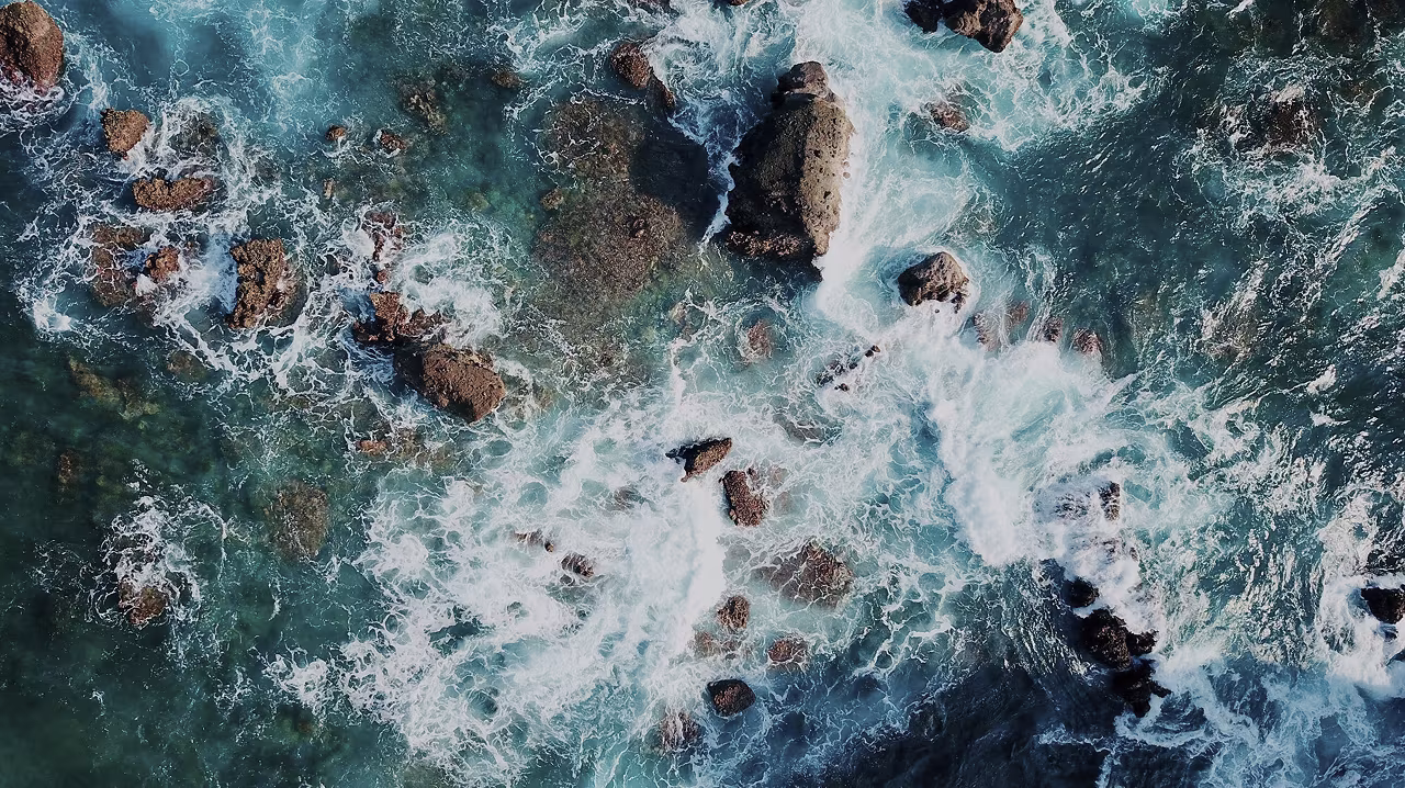 Rocas entre las olas del mar vistas desde arriba, imagen de los beneficios y riesgos de las sustancias psicodélicas