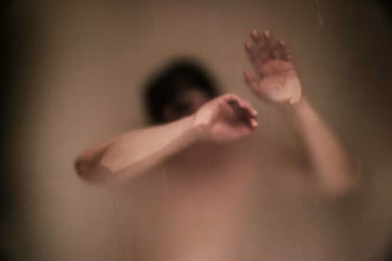 Persona tras un cristal empañado con la mano levantada, imagen de los psicoplastógenos para tratar el TEPT