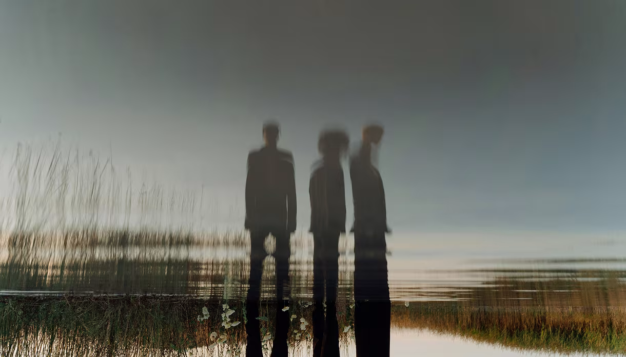 Siluetas de personas reflejadas en el agua de un lago, imagen de la visión de Fundación Inawe sobre la salud mental